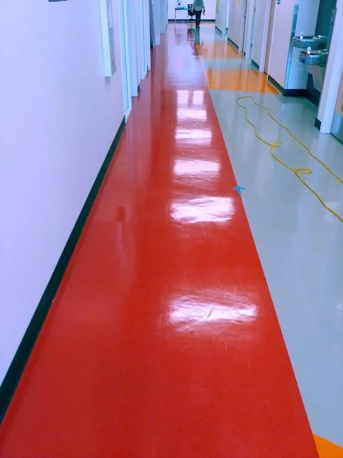 A long hallway with a red floor and white walls