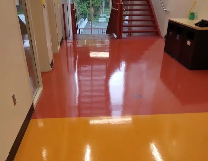 A hallway with a red and orange floor and stairs.