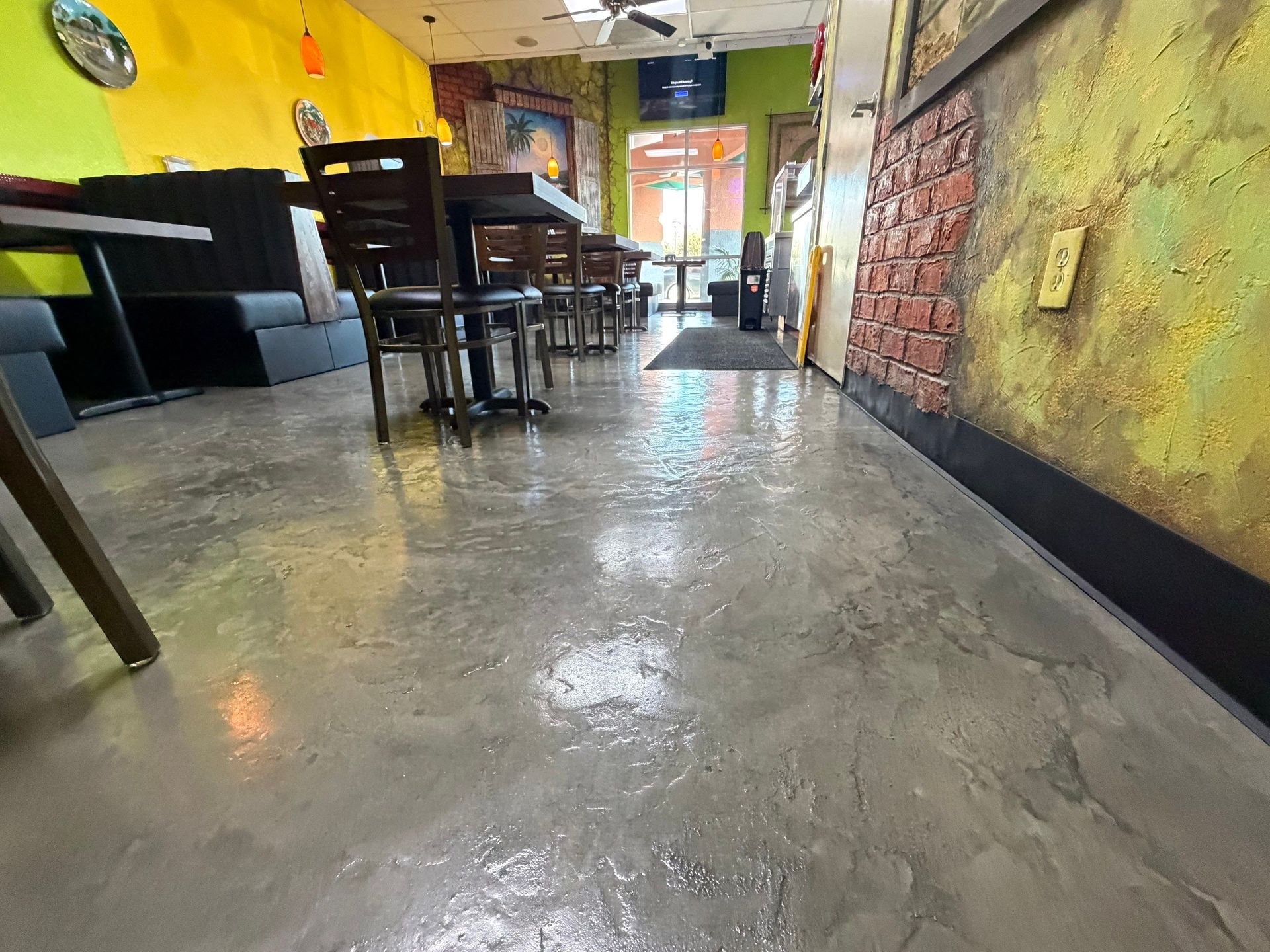 Cozy café interior with wooden tables and chairs, yellow walls, and a shiny concrete floor.