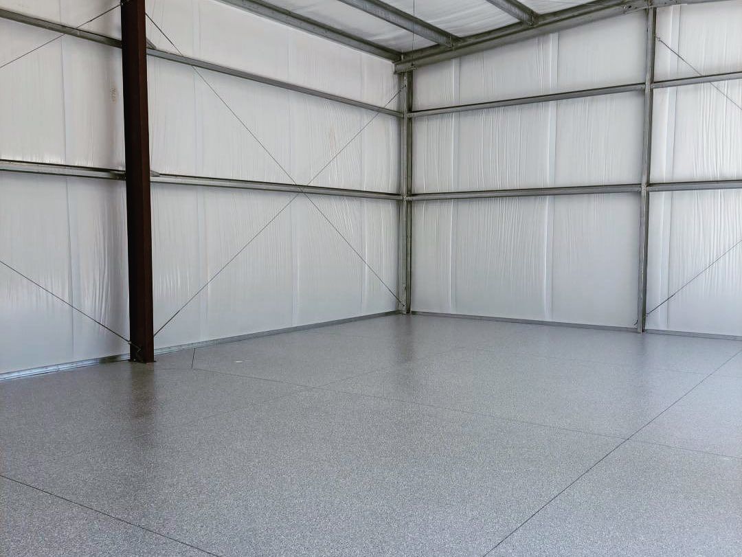 Empty metal-walled warehouse interior with a gray concrete floor