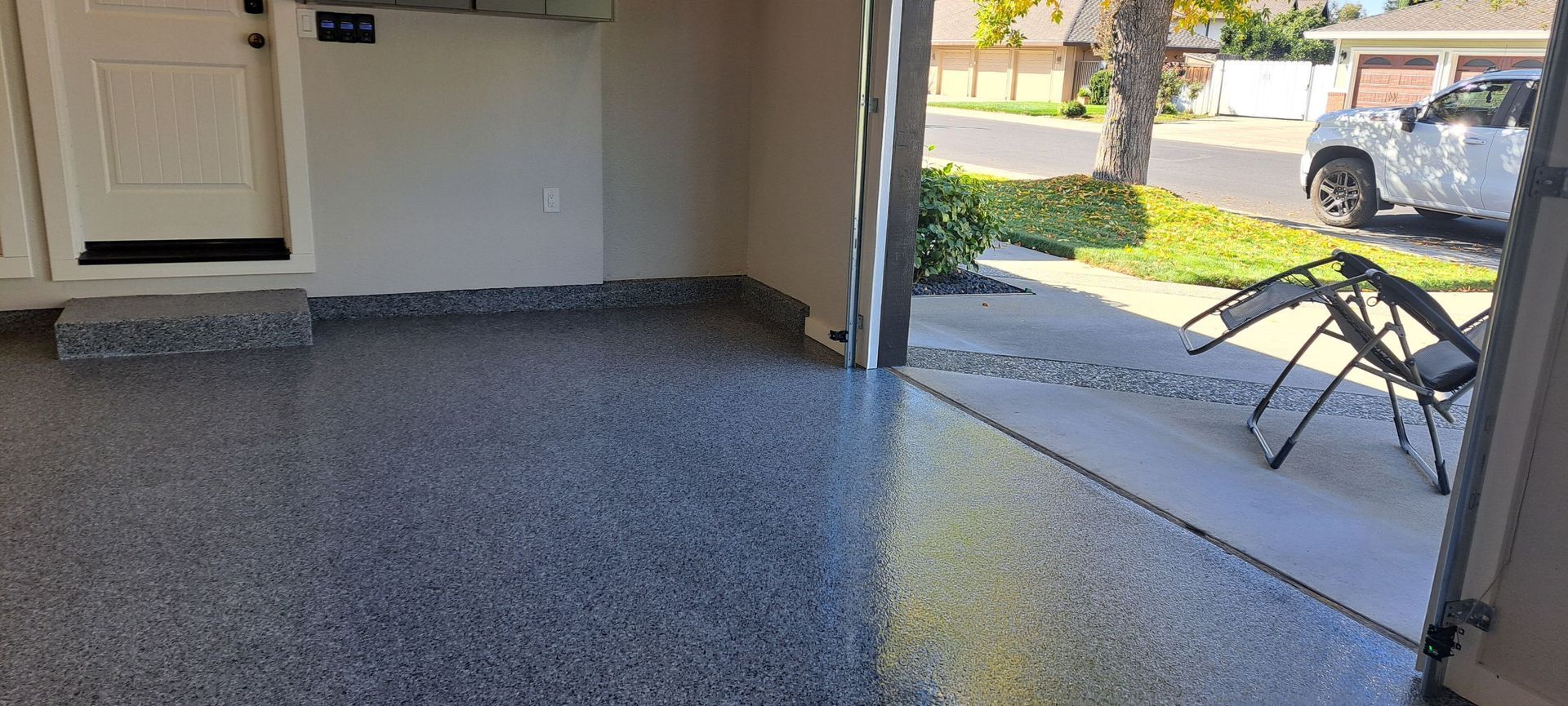 Covered patio with speckled epoxy floor, bike at right, and a yard visible beyond the open doorway
