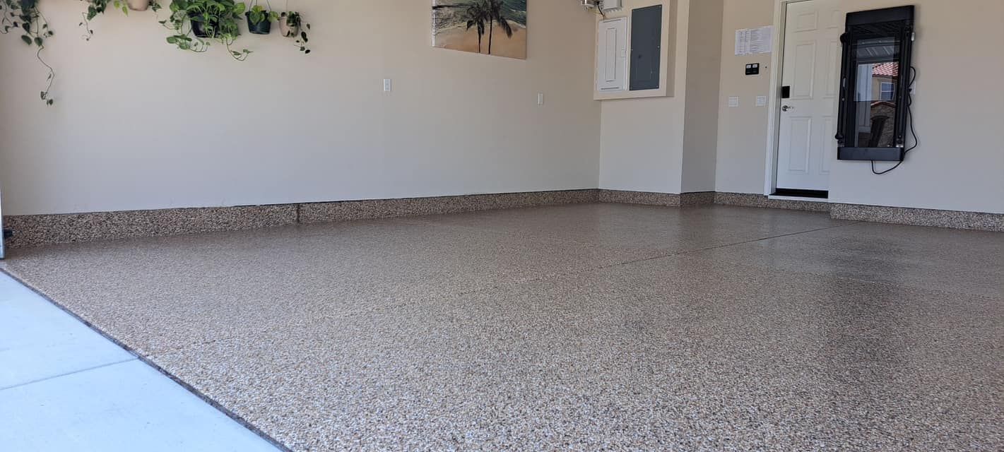 Empty covered patio with speckled concrete floor and beige walls; small windows and a door on the right.