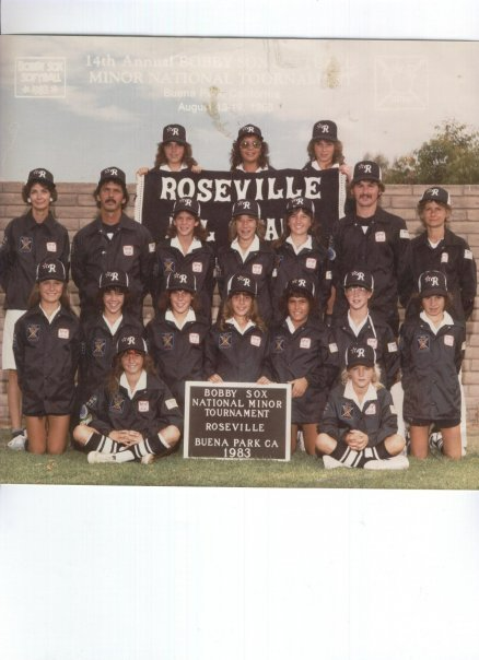 Group photo of uniformed Roseville softball team posing on a field with championship sign
