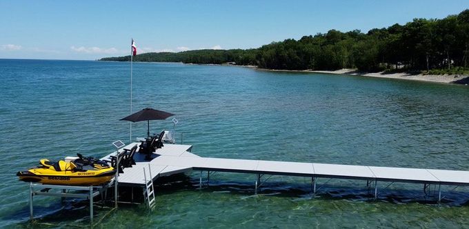 An image of a long pipe dock featuring a bright yellow jet ski, leading into beautiful blue waters