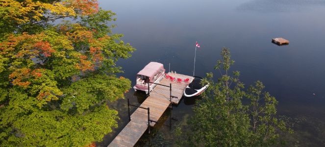 The A breathtaking aerial view of a calm lake front featuring a wood dock and trees