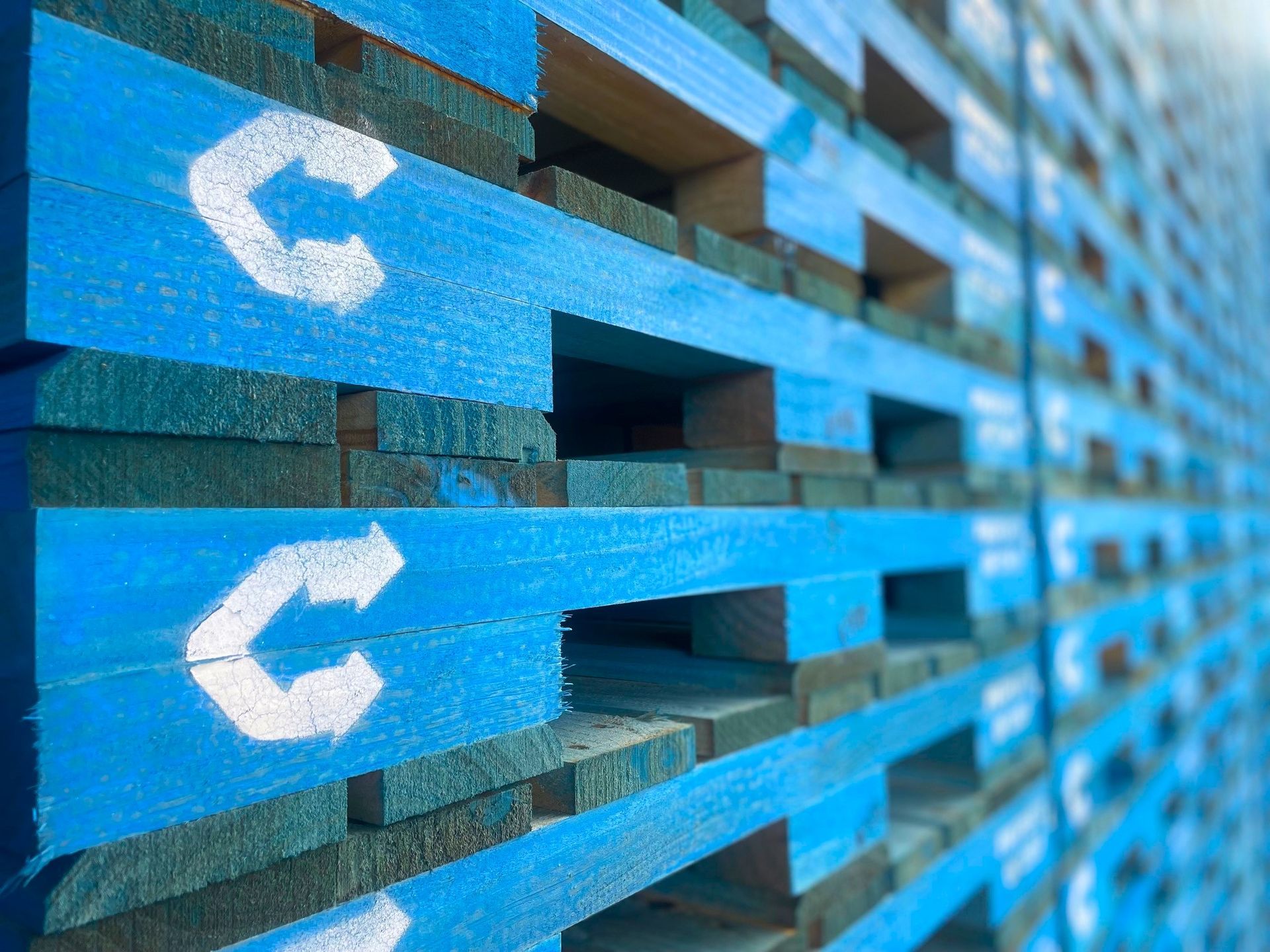 Stacked wooden planks in a lumber yard, showing cut timber with rough ends and warm brown tones