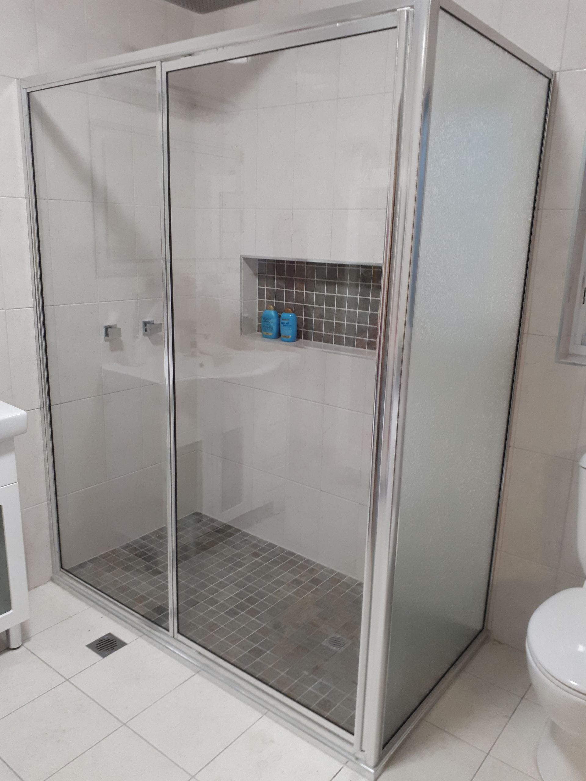 Bathroom with a frosted glass shower, white toilet and vanity, and overhead rain shower head — Advancetech Glass & Glazing in Wulguru, QLD