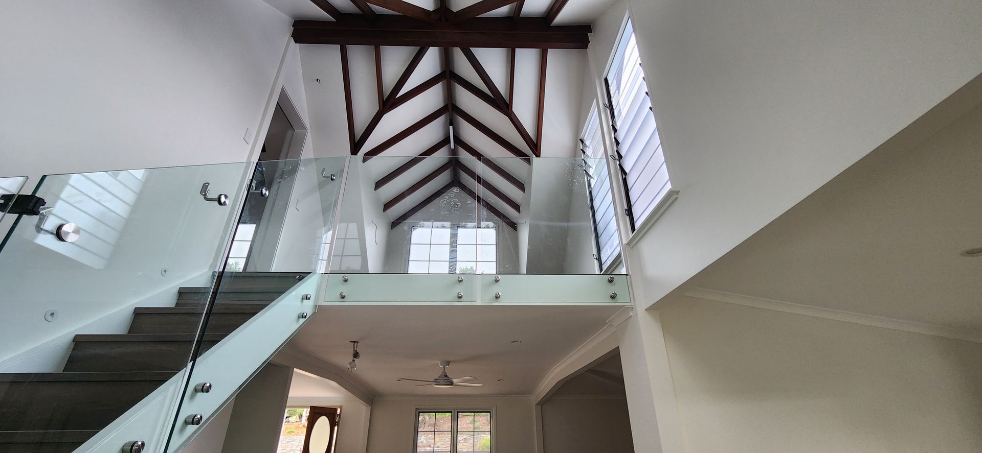Interior of a room with a pitched ceiling, dark wooden beams, a window, and white walls — Advancetech Glass & Glazing in Wulguru, QLD
