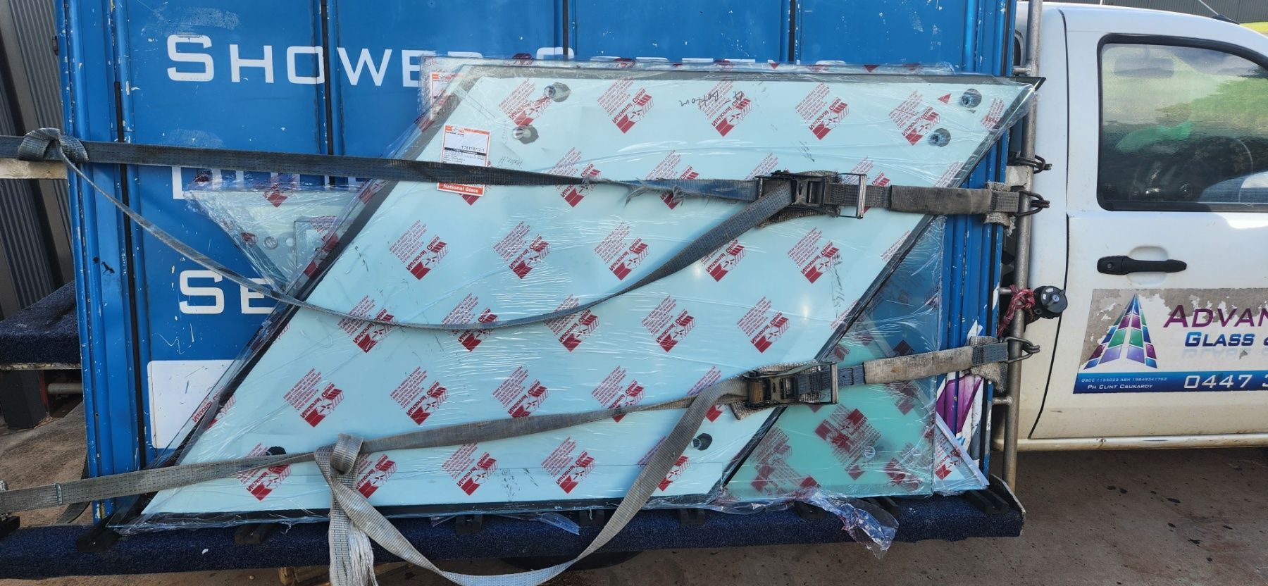 Glass panels strapped to a truck for transport; panels are covered with blue and red packaging — Advancetech Glass & Glazing in Wulguru, QLD