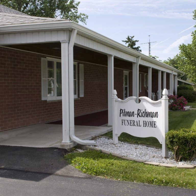Brick funeral home exterior with white columns and a sign reading “Pruett-Richmond Funeral Home.”