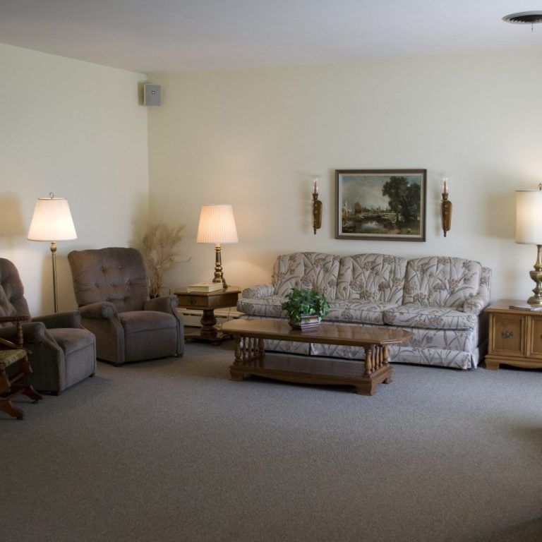 Cozy living room with a sofa, recliners, lamps, coffee table, and framed wall art