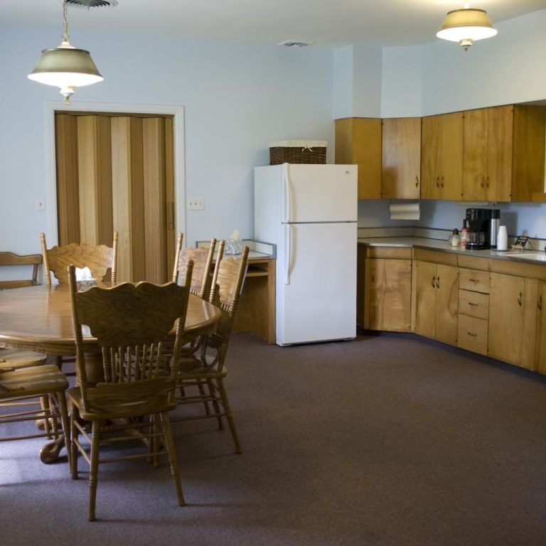 Kitchen and dining area with wooden table and chairs, white refrigerator, and wood cabinets