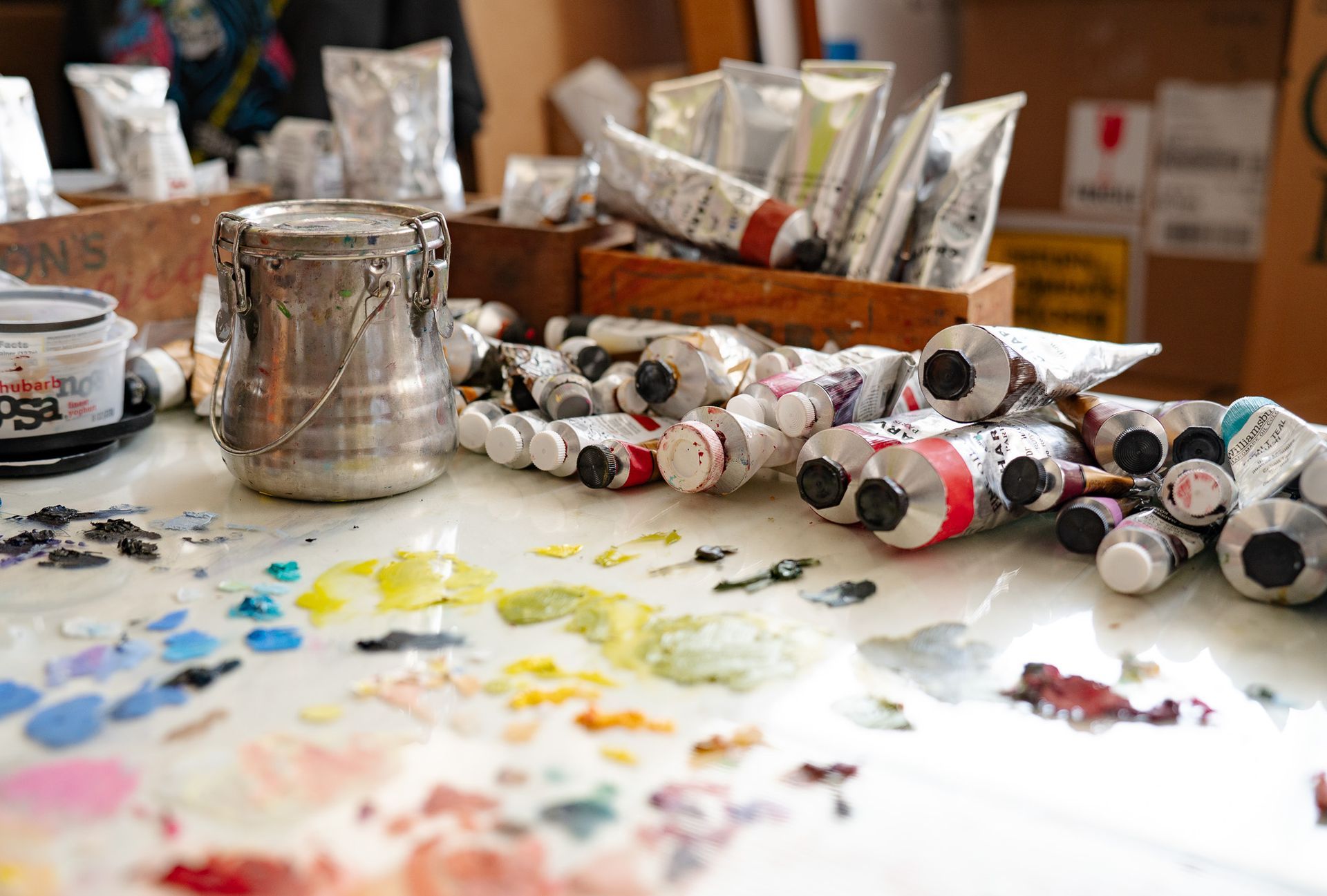 Image of the artist's palette with dried paint, tubes of paint, and other accessories.