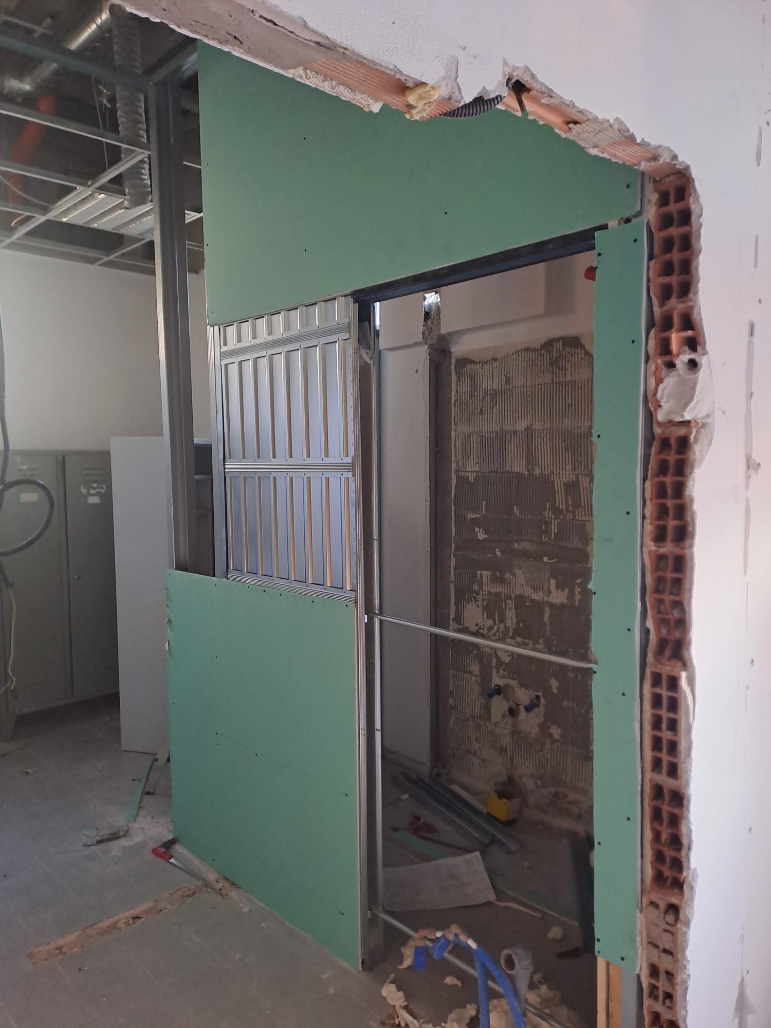 Divisorio verde danneggiato con un vano porta aperto in un cantiere di costruzione o ristrutturazione