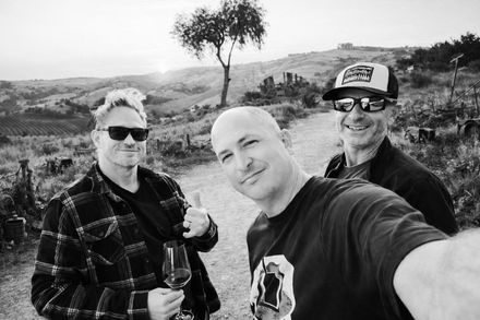Dane Curley, Matt Reese and Keith Robinson taking a black-and-white selfie in a hilly outdoor landscape