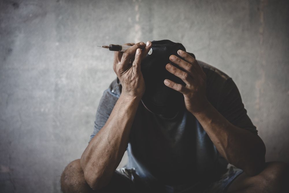 a man is sitting on the floor holding a cell phone in front of his face .