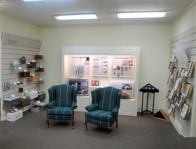 Small waiting room with two teal armchairs, brochure racks, display shelves, and a lit window opening.