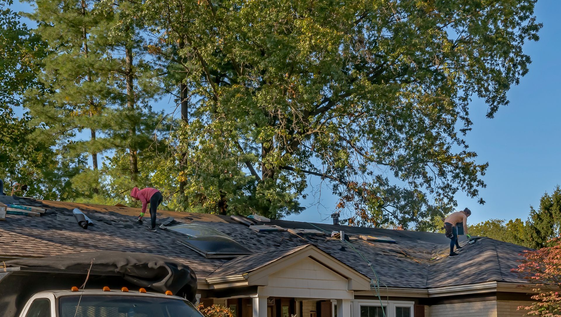 Roofers removing old material from a house in preparation for a roof restoration Roofers removing old material from a house in preparation for a roof restoration