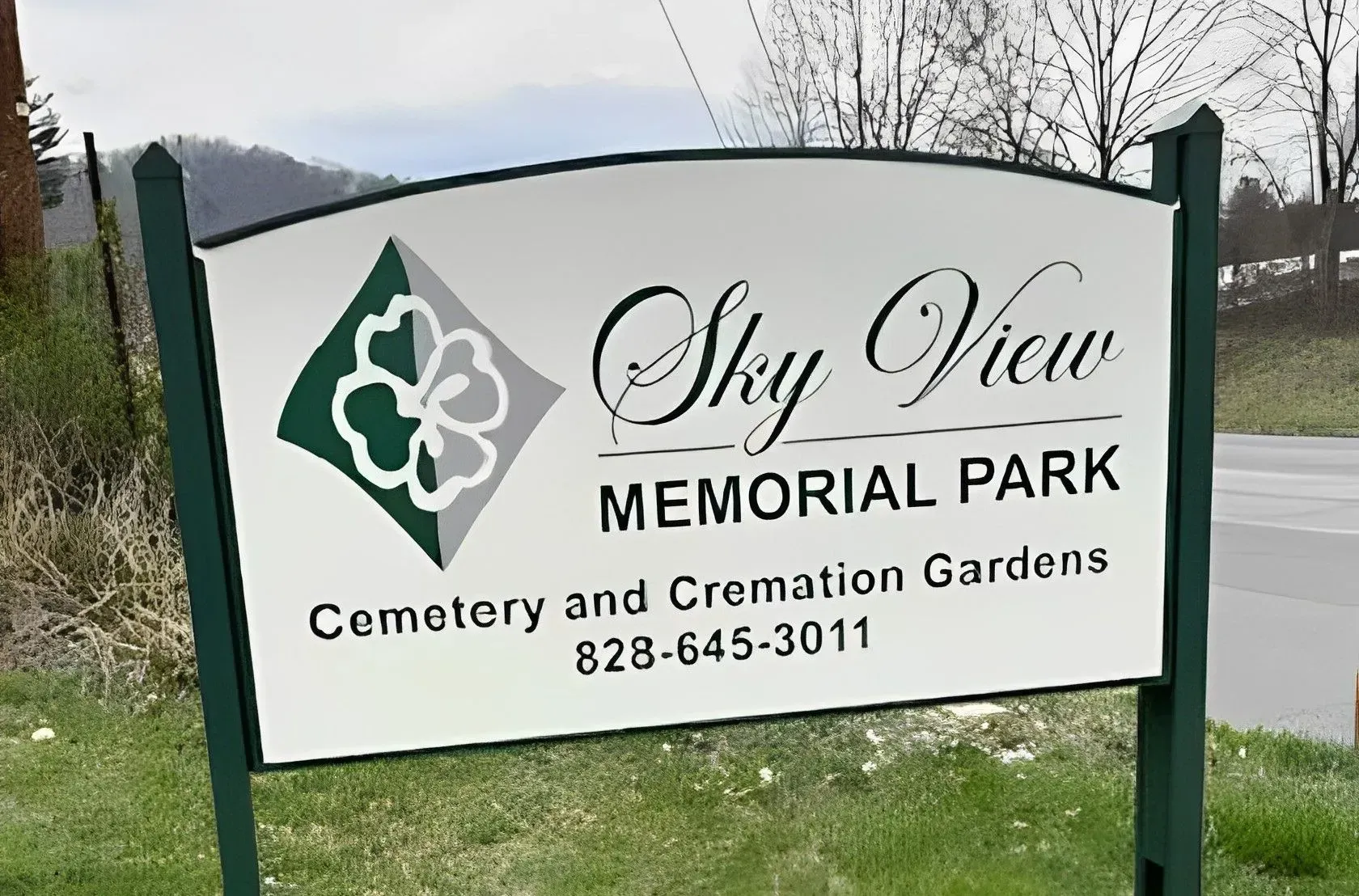 Sky View Memorial Park sign with logo, cemetery and cremation gardens, near a road and trees