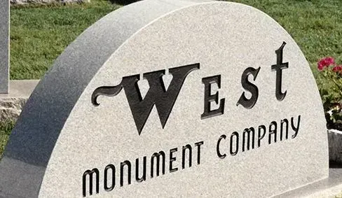 West Monument Company sign on a gray stone monument outdoors