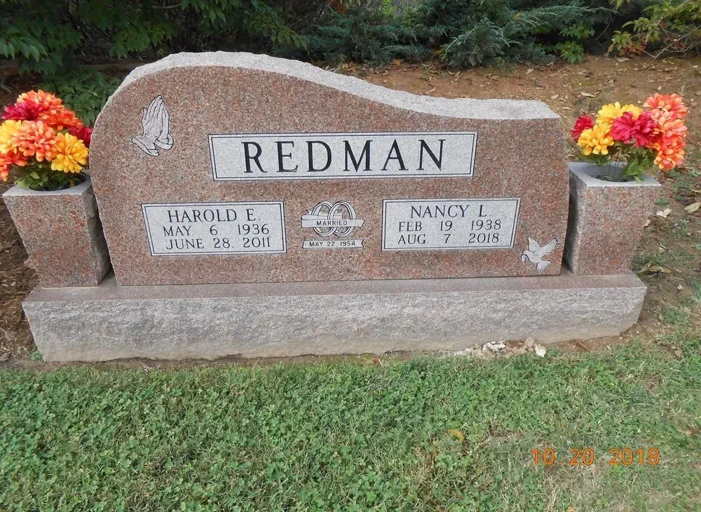 Redman family gravestone with flowers on both sides in a cemetery