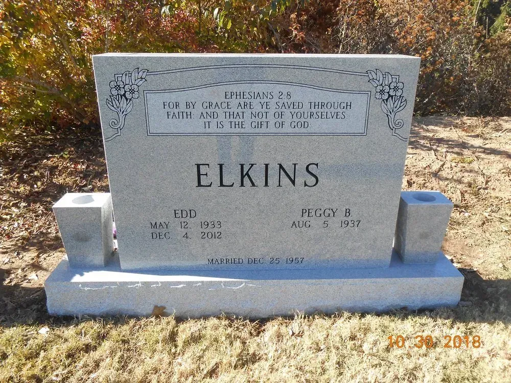 White gravestone with ELKINS engraved, set in a grassy cemetery with autumn leaves.