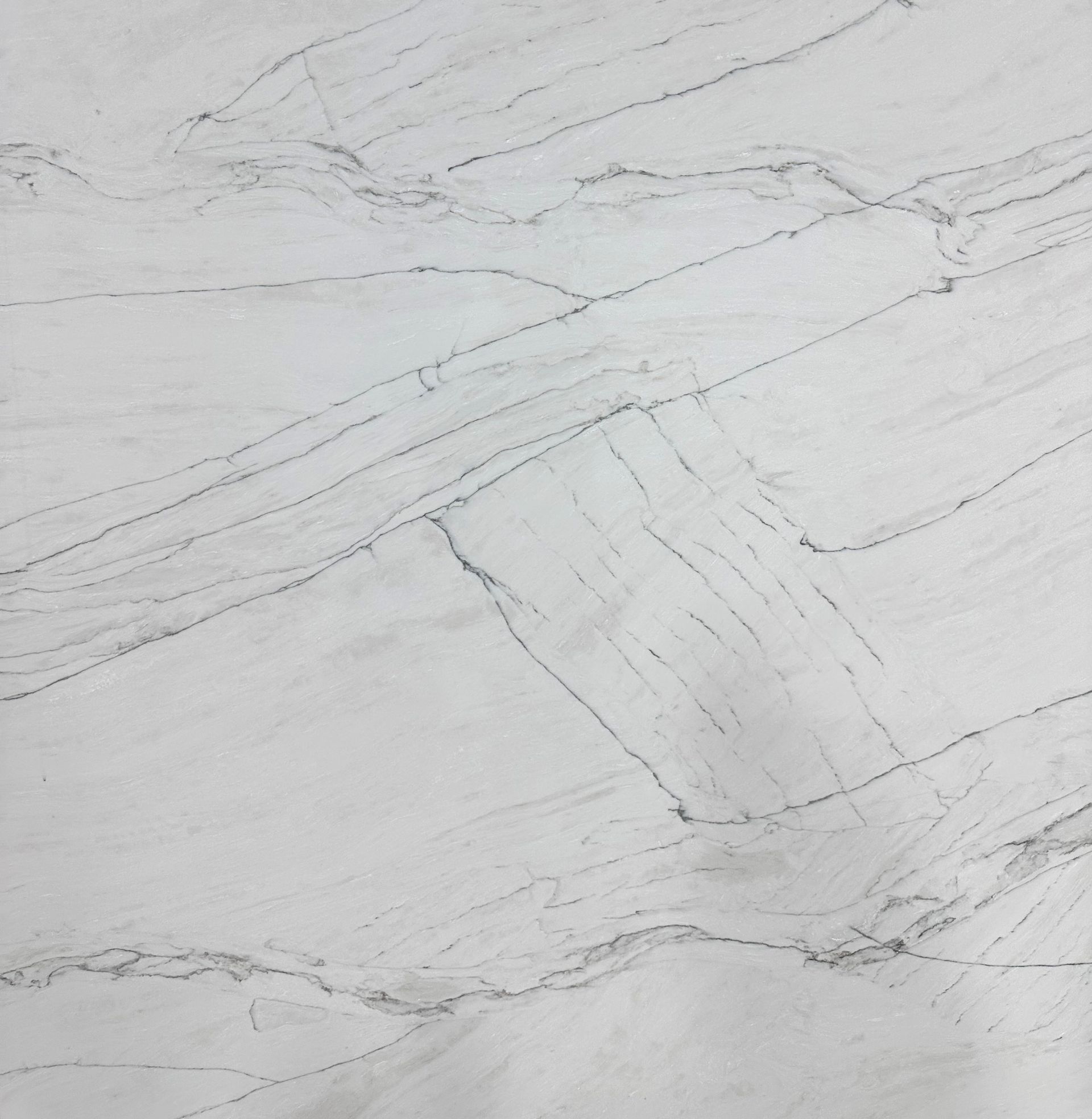 A slab of white stone with thin, dark gray, irregular veining running diagonally across the surface.