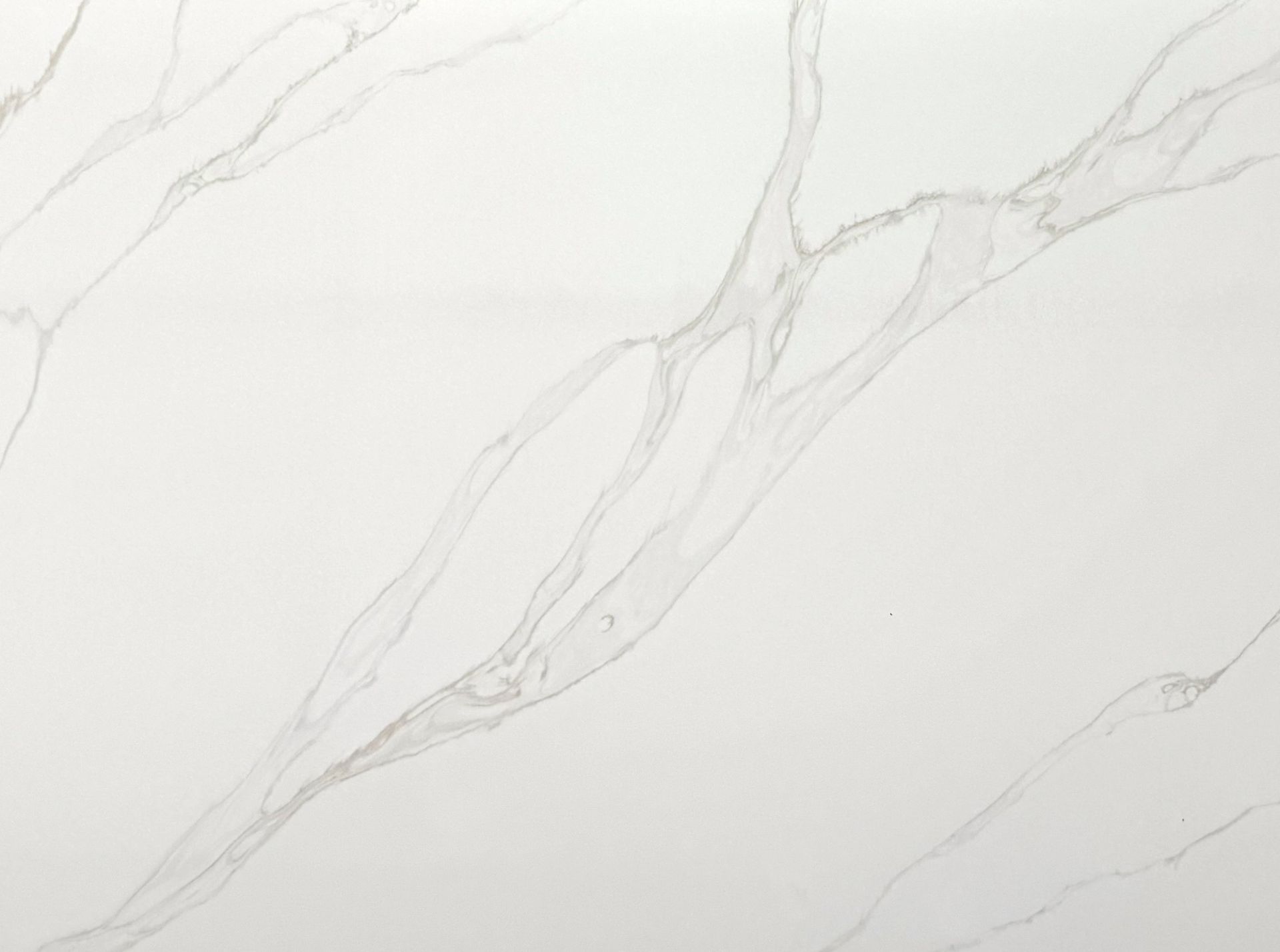 White marble surface with subtle, branching grey and rust-colored mineral veins.