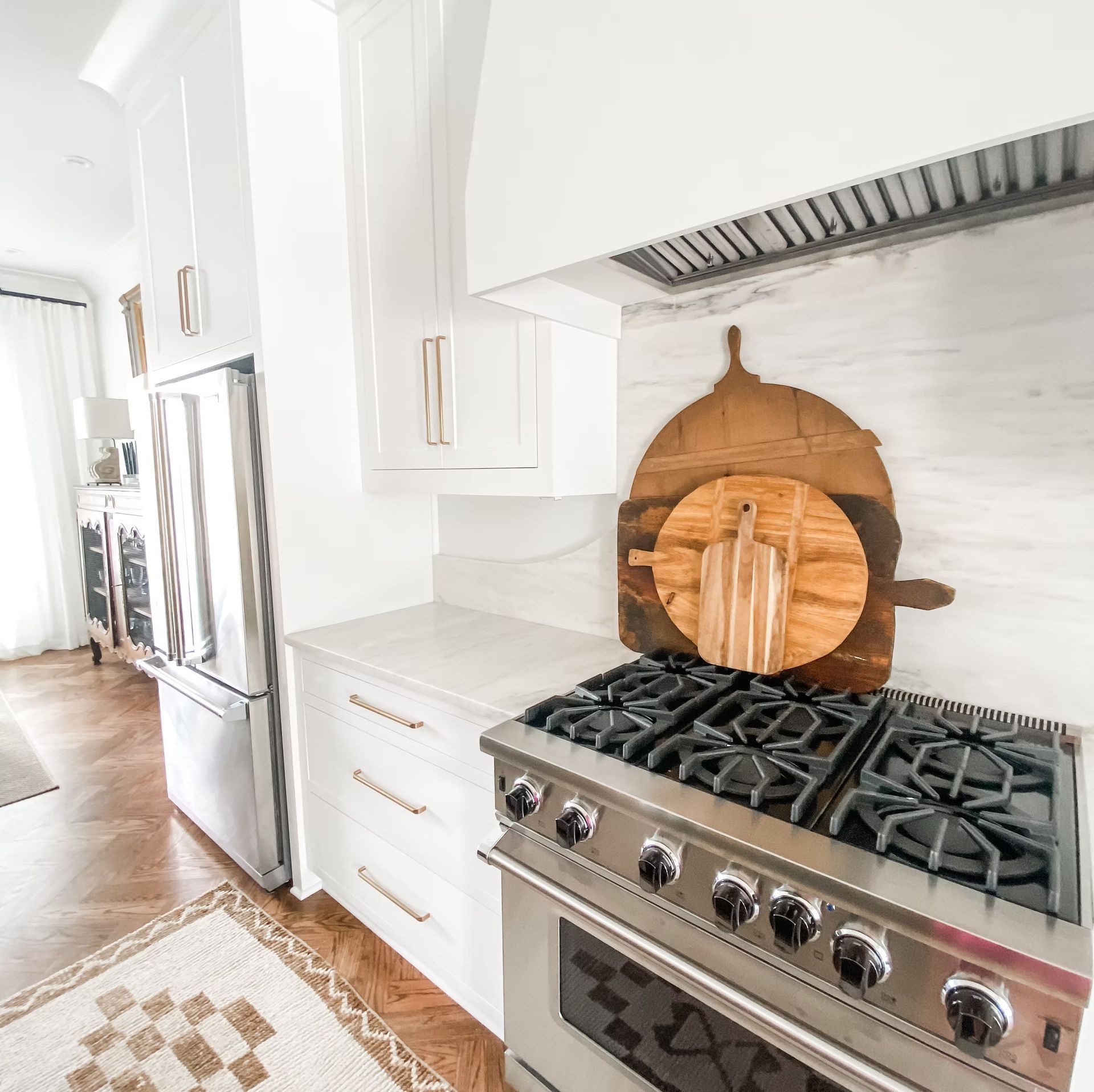 Modern kitchen with stainless steel appliances, white cabinets, and wooden cutting boards.