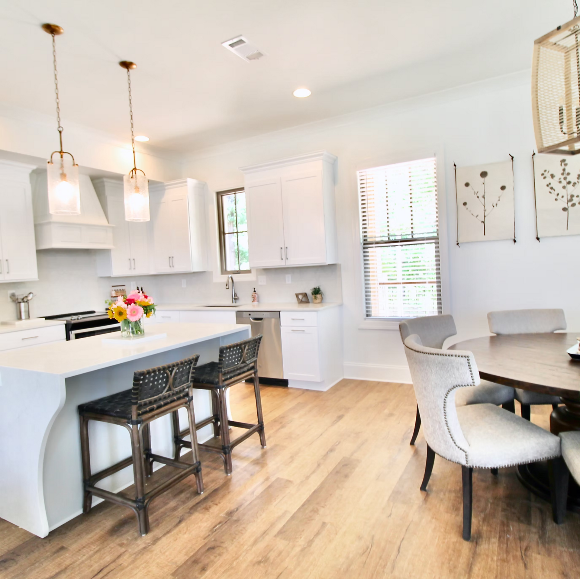 Bright kitchen with white cabinets, island with stools, and dining area with round table.