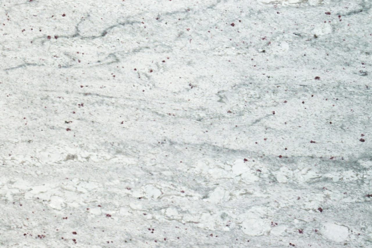 White granite countertop with gray veins and small red speckles.