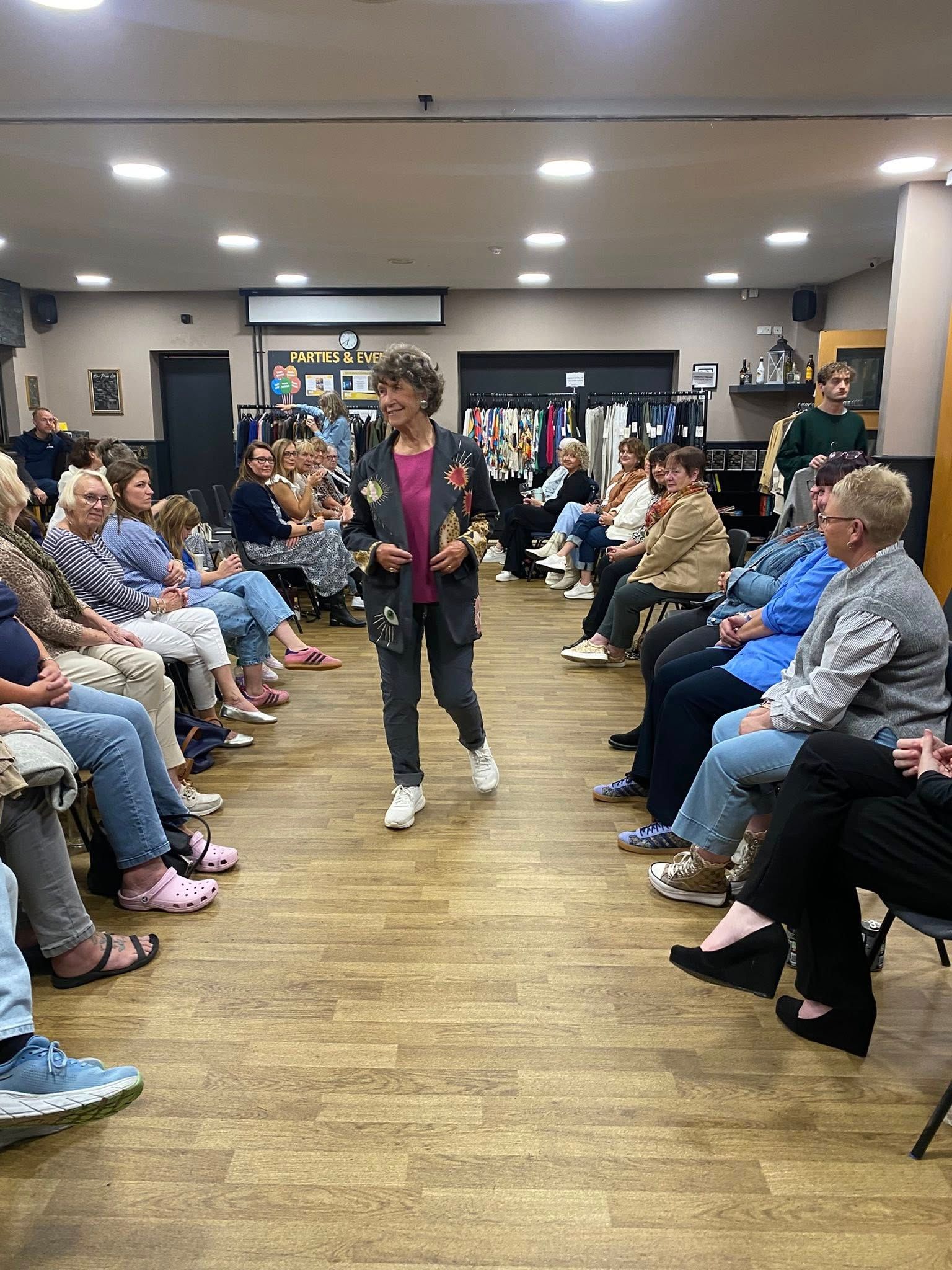 Woman speaking in a hall aisle between seated audience rows