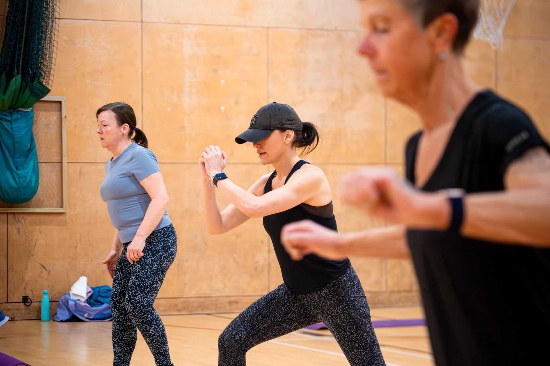 People exercising in a studio, including a woman in black leading a workout class