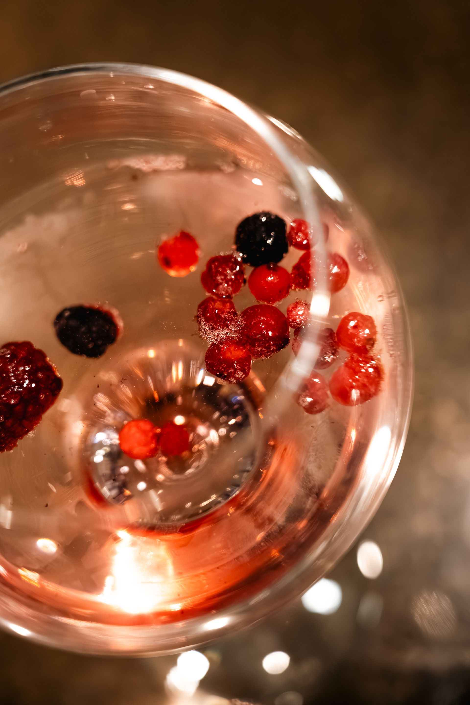 Top-down view of a glass with red and black berries floating in a drink