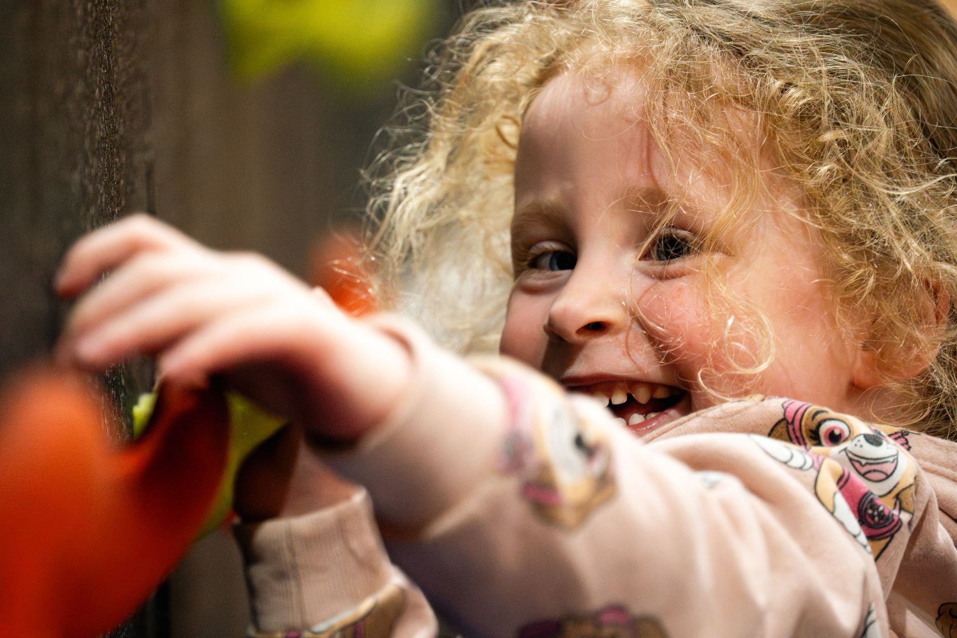 Smiling child reaching toward colorful autumn leaves outdoors