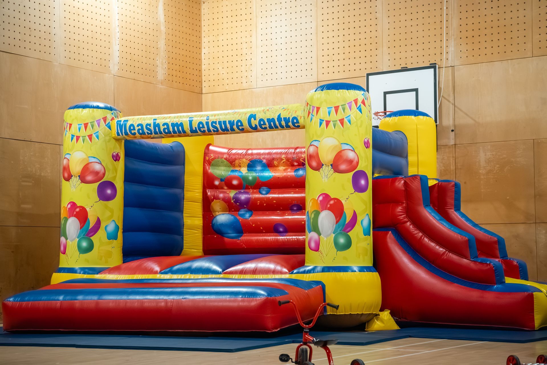 Colorful indoor inflatable obstacle course with slides and ball pillars on a gym floor