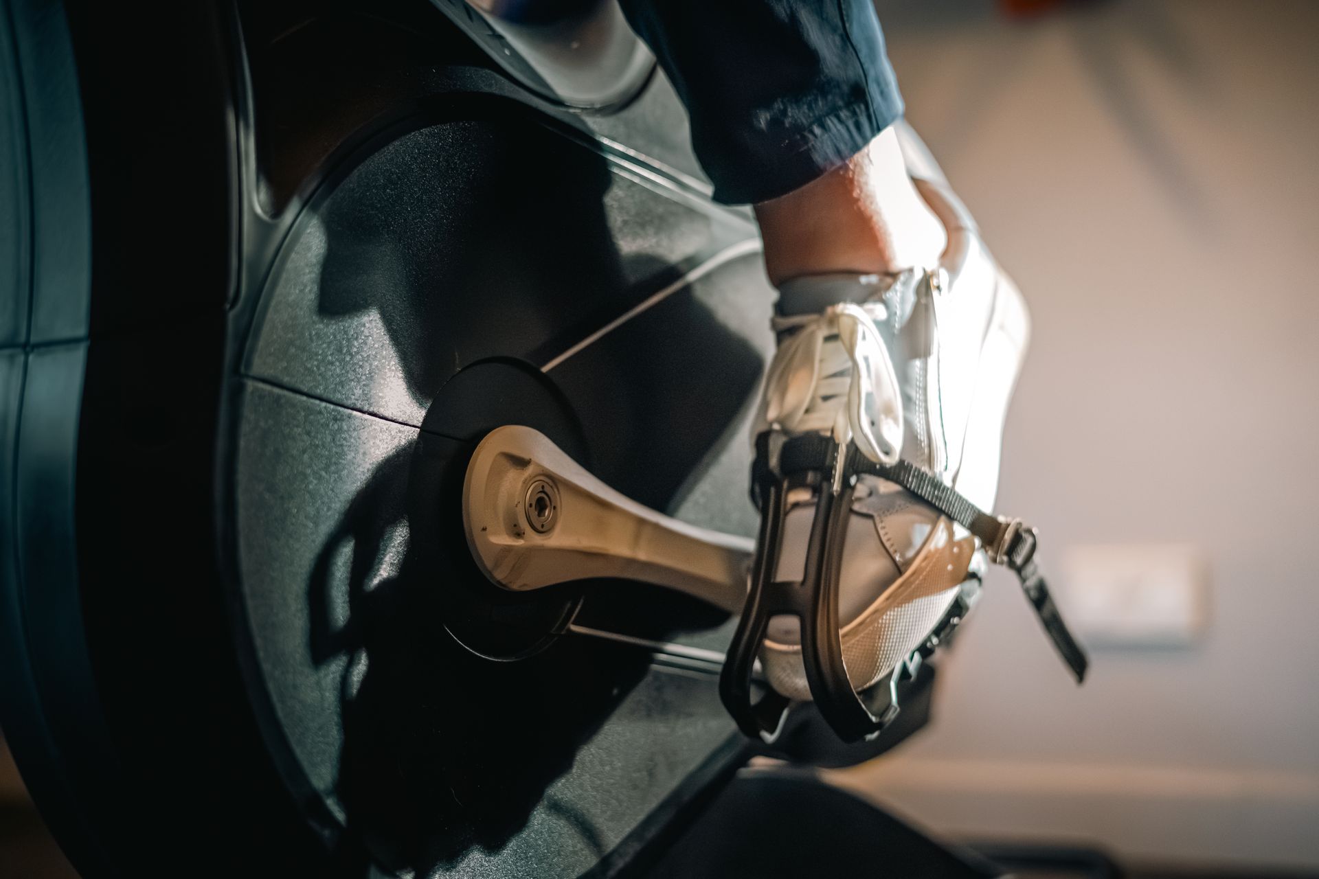 Close-up of a cyclist’s shoe clipped into a bicycle pedal, with the wheel and frame visible