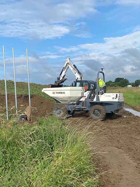 a DHS Plant Hire Terex swivel tip dumper  tipping soil in a field