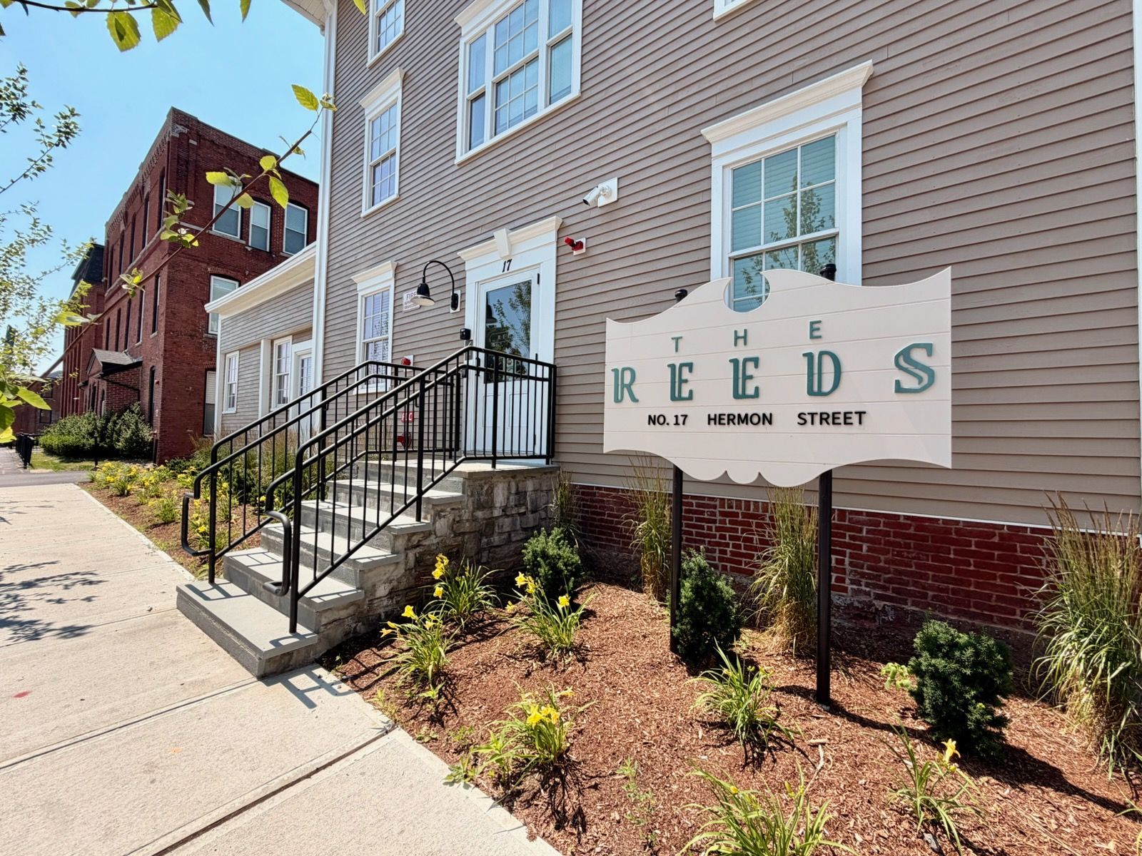 The exterior of The Reeds at 17 Hermon Street, beside a historic red-brick mill in Worcester's Canal District