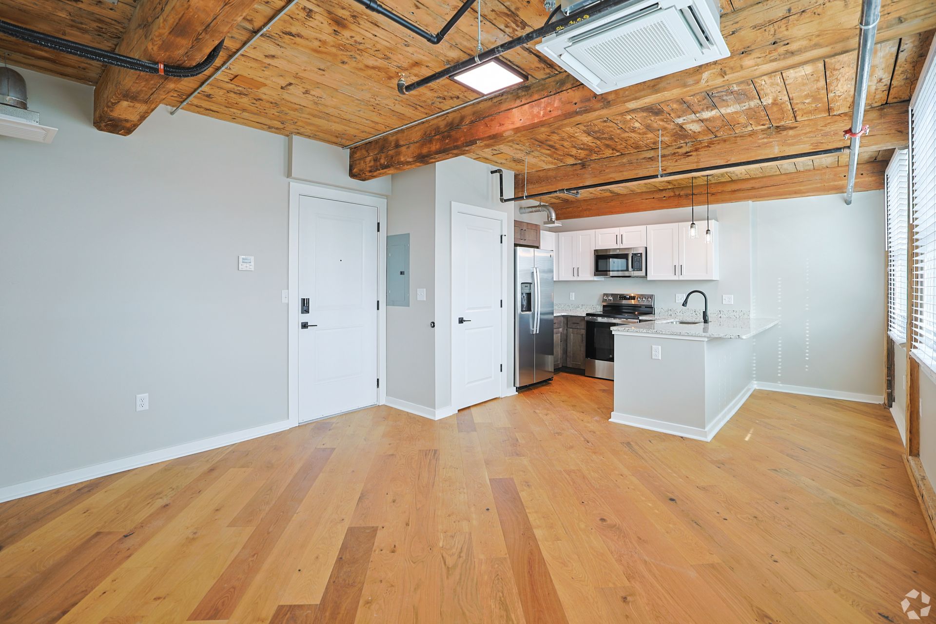 An open loft apartment at The Reeds with wide-plank hardwood floors and an exposed timber ceiling