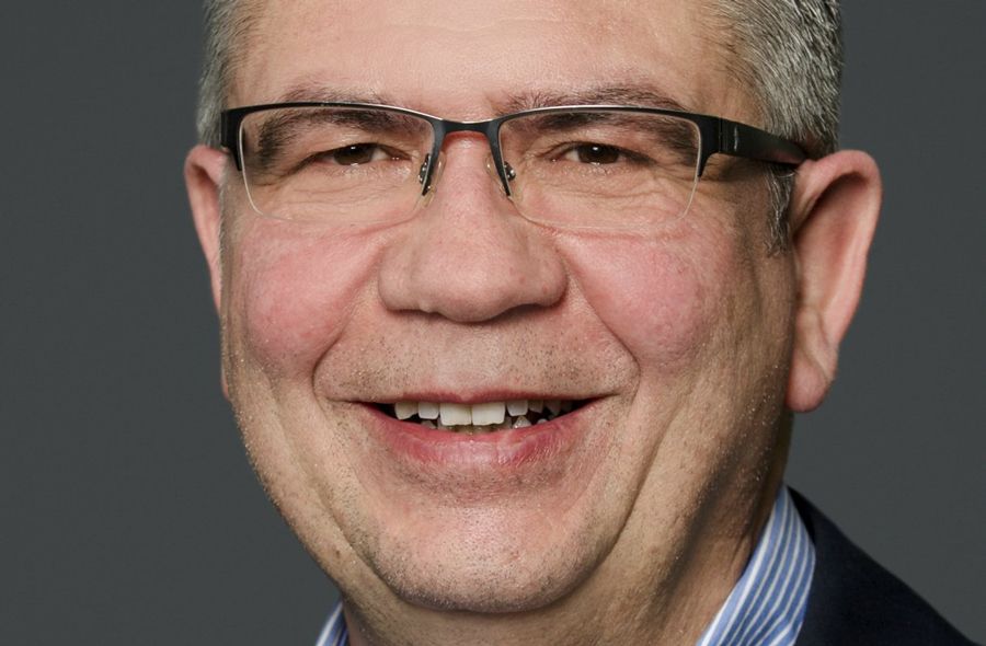 Ein Mann mit Brille und Anzug namens Nicola Manolio lächelt in die Kamera.