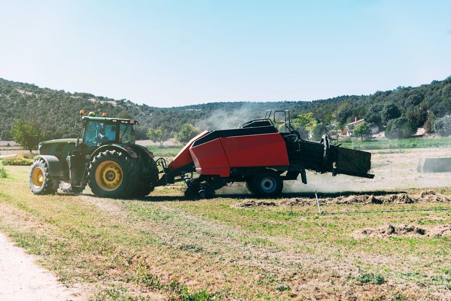 Un tracteur charge du foin dans une remorque dans un champ.