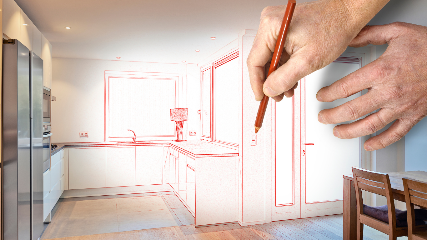 Hands sketching a bright kitchen interior renovation plan with red pencil lines.