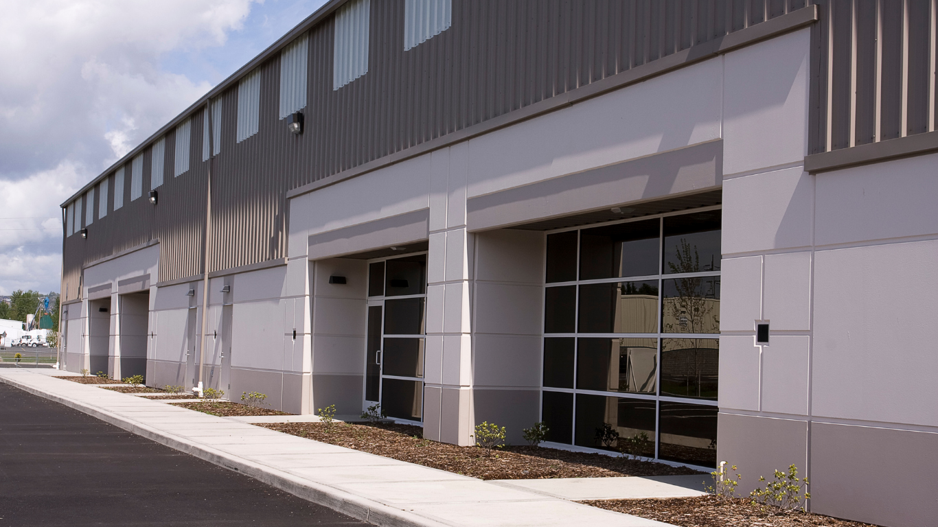 Modern industrial warehouse exterior with gray facade, loading bays, and a paved driveway