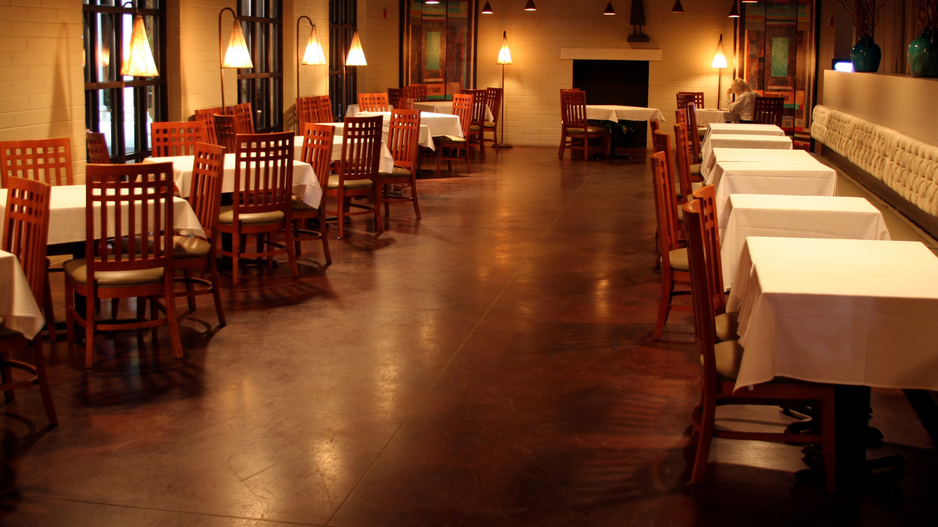 Empty restaurant dining room with wooden chairs, tables, and warm amber lighting