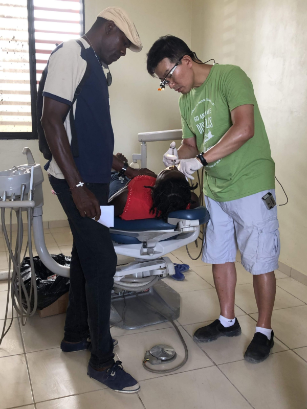 Two men examining equipment beside a hospital bed in a clinical room