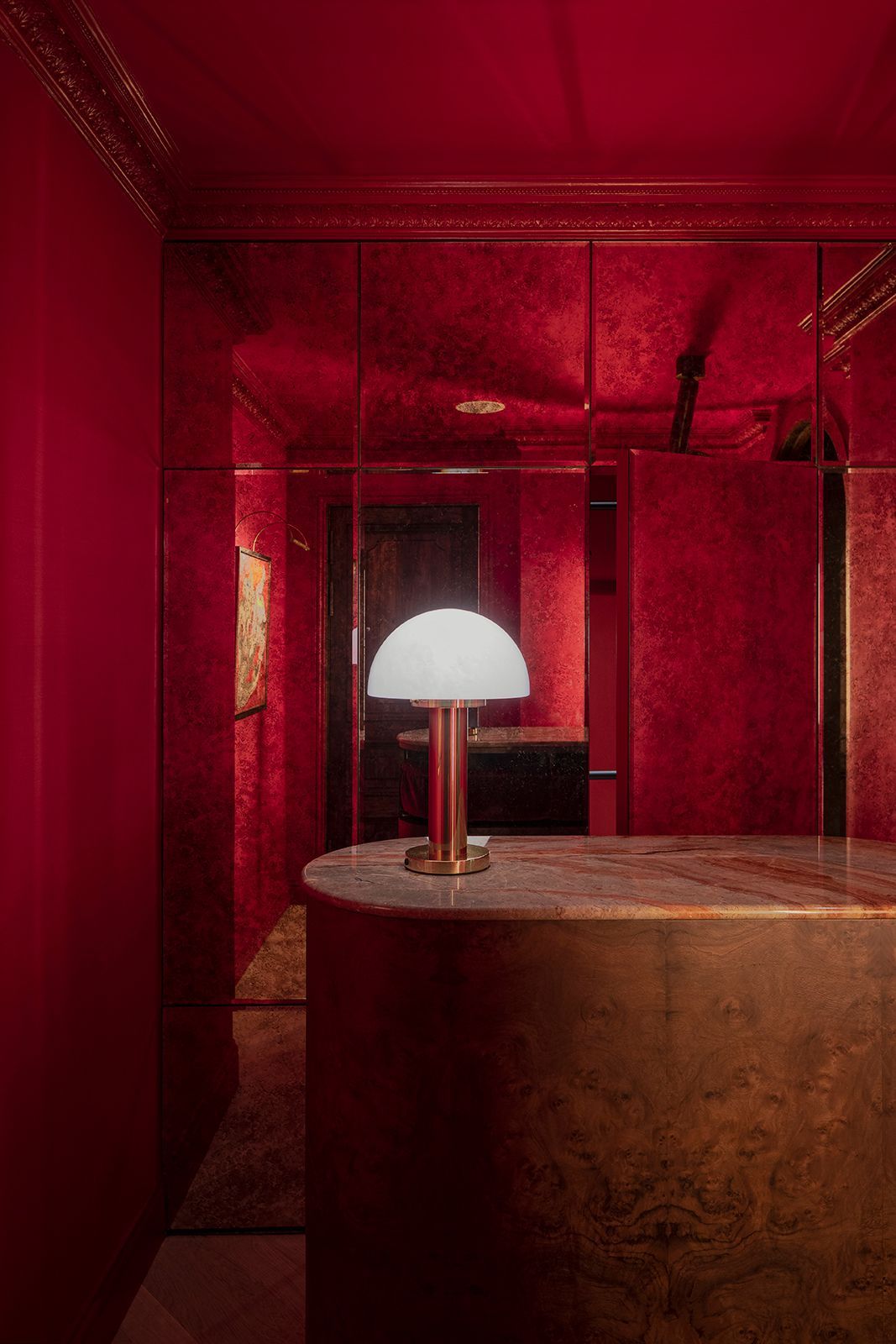 Red-walled, mirrored interior with a gold counter and lamp; a doorway is visible in the back.
