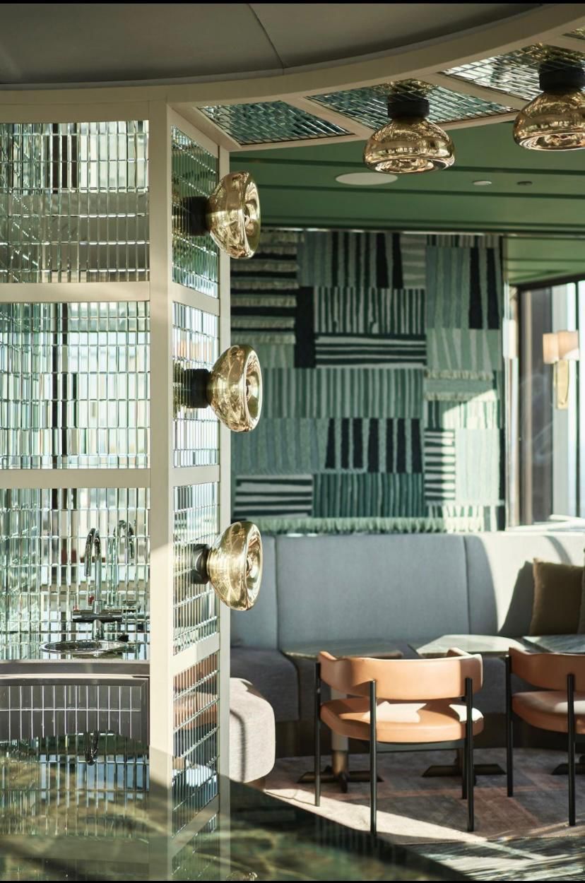 Stylish restaurant interior. Green and gold accents, glass brick wall, modern furniture, and a cozy seating area.