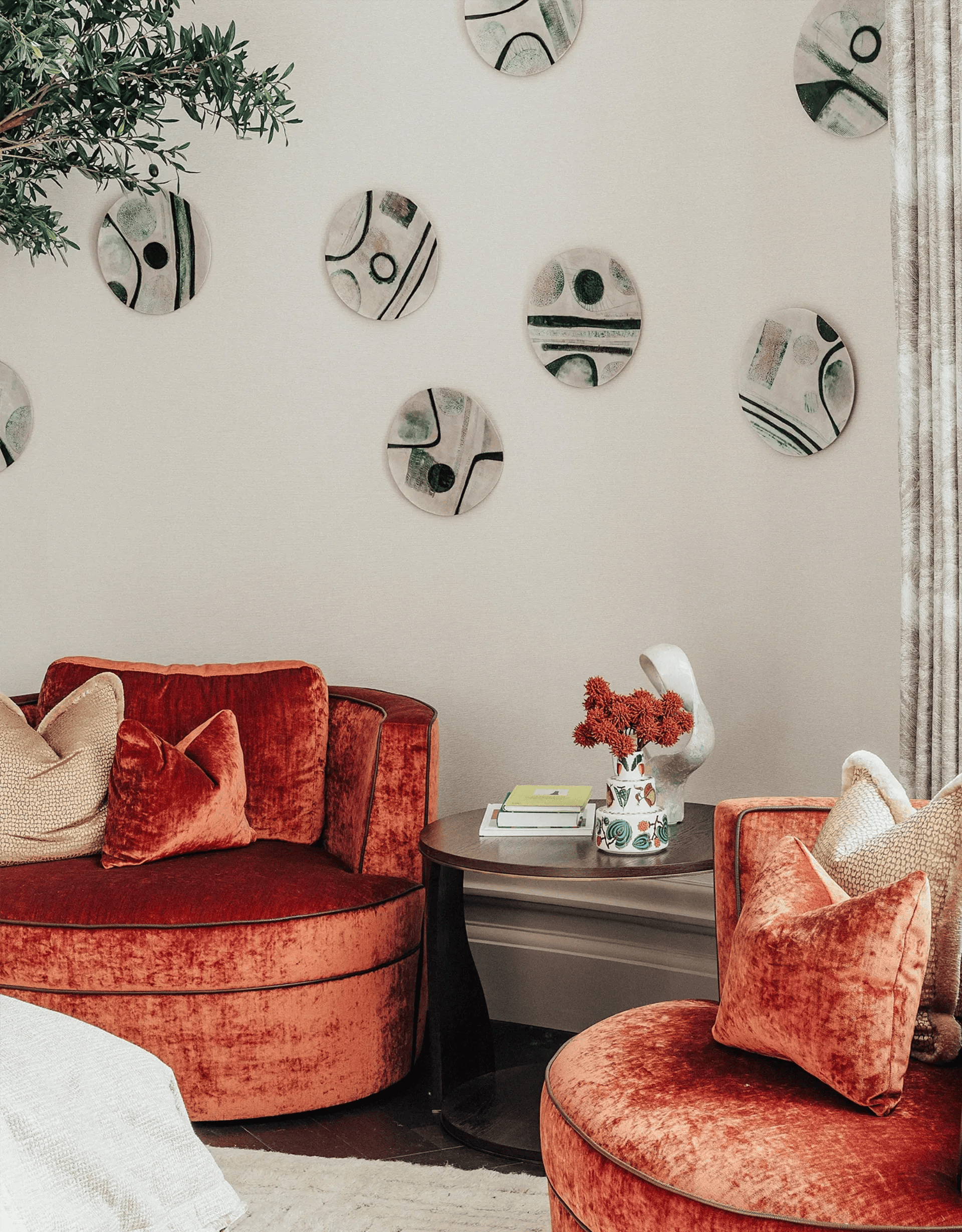 Red velvet seating area, wall art, small table with decor, neutral walls.