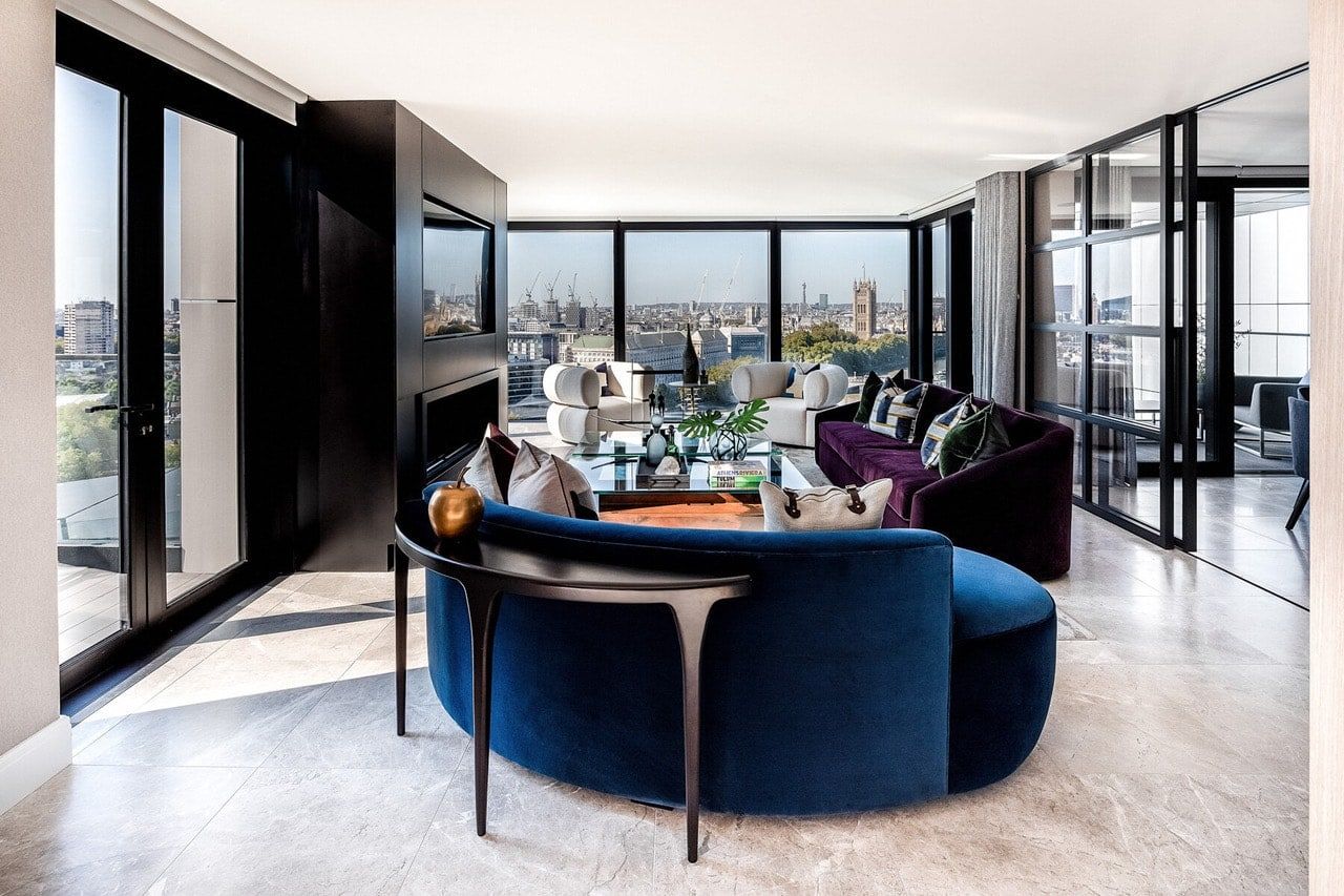 Stylish living room with blue curved sofa, city view, and black accents.
